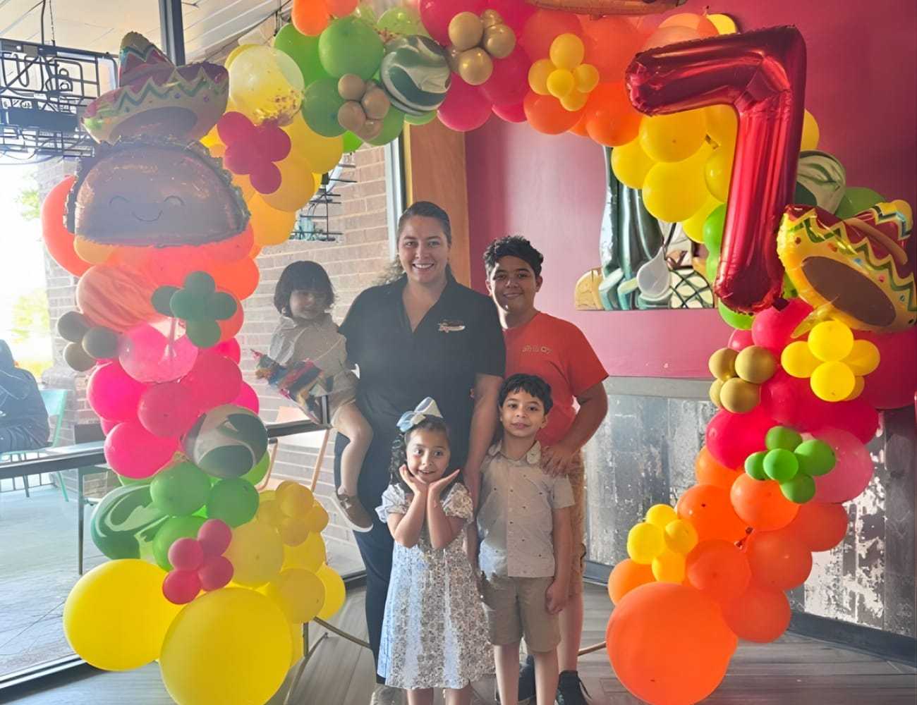 Family celebration with colorful balloon arch and sombrero decor.